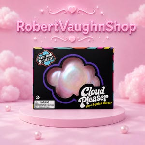 May include: A black rectangular toy box featuring a cloud-shaped cutout revealing an iridescent, pearlescent squishy toy. The packaging displays the text Soft Doh Squish!, Cloud Pleaser, pure Squish Bliss!, and a 3+ age rating with a warning label.