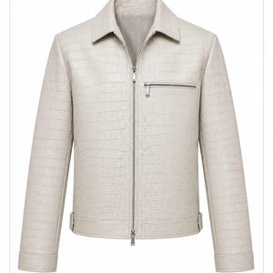 Könnte beinhalten: Eine hellbeige Jacke mit texturiertem Krokodilleder-Muster, spitzem Kragen und einem durchgehenden silberfarbenen Reißverschluss. Das Kleidungsstück verfügt über eine horizontale Reißverschlusstasche auf der Brust und lange Ärmel mit geknöpften Manschetten.