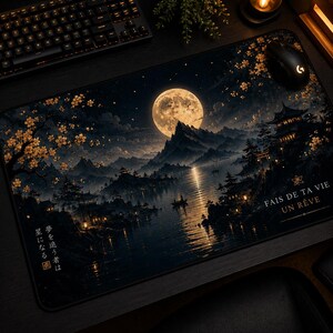 Peut inclure: Un grand tapis de souris rectangulaire représentant un paysage nocturne avec une pleine lune, des montagnes et un plan d'eau. Le motif comprend des bâtiments de style japonais, des fleurs de cerisier et du texte en anglais et en japonais. Une souris et un clavier noirs sont visibles.