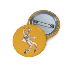 Könnte beinhalten: Ein runder Ansteckbutton mit senfgelbem Hintergrund und einer schwarz-weißen Tuschezeichnung einer Giraffe, die ein gestreiftes Hemd, eine Jacke und eine Hose trägt und in einer dynamischen Tanzpose mit erhobenem Arm dargestellt ist.