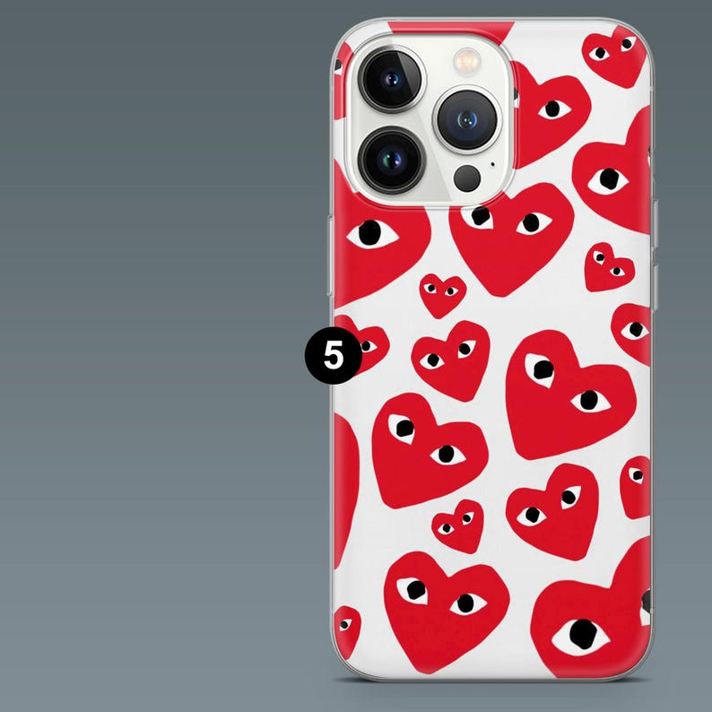May include: A clear phone case featuring a pattern of red hearts with black eyes on a white background. The case has a camera cutout and a black number 5 in a circle.