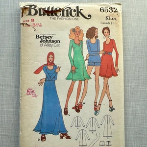 Può includere: Una busta di cartamodello vintage con un design di Betsey Johnson di Alley Cat. Il cartamodello è per un vestito e include le taglie 5-13. La busta è gialla con uno schema di colori rosso, bianco e blu.