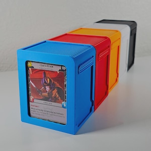 May include: A row of five rectangular plastic card storage boxes in blue, red, orange, white, and black. The front blue box features a clear display window holding a Darth Revan trading card with visible text including Force-Sith and Restore 1.