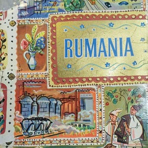 Pode incluir: Uma capa de livro retangular com a palavra RUMANIA em azul sobre um fundo dourado. A ilustração inclui uma cena de rua urbana, um vaso de flores, silos industriais com um vagão de carvão e duas figuras com roupas tradicionais e ovelhas.