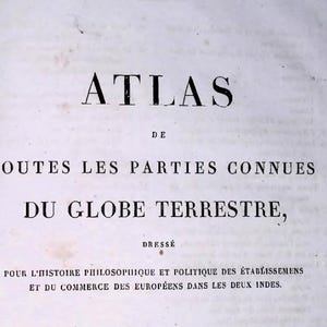 Op de afbeelding: Een witte pagina met zwarte gedrukte tekst: ATLAS DE TOUTES LES PARTIES CONNUES DU GLOBE TERRESTRE, DRESSÉ POUR L'HISTOIRE PHILOSOPHIQUE ET POLITIQUE DES ÉTABLISSEMENS ET DU COMMERCE DES EUROPÉENS DANS LES DEUX INDES.