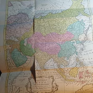 May include: A vintage map of Asia, featuring detailed geographical information and historical text. The map is colored in pastel hues, with countries and regions clearly delineated. The title "Improved Map of Asia" is visible, indicating its historical significance.
