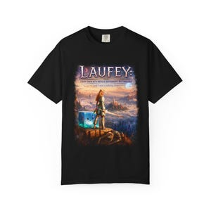 Puede incluir: Una camiseta negra de manga corta con un estampado gráfico de fantasía. El texto dice LAUFEY: I GOT ISEKAI'D INTO A DIFFERENT MYTHOLOGY (and I met a talking slime). La imagen muestra a un guerrero en un acantilado con un cubo azul brillante.