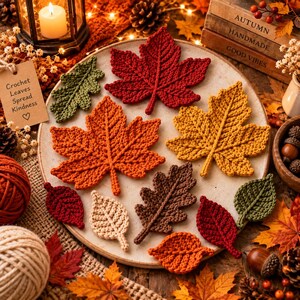 Peut inclure: Une collection de feuilles au crochet de formes et de couleurs automnales variées, incluant rouge, orange, jaune, marron, vert et crème, disposées sur une assiette ronde en céramique. Une étiquette en papier beige porte le texte Crochet Leaves Spread Kindness.