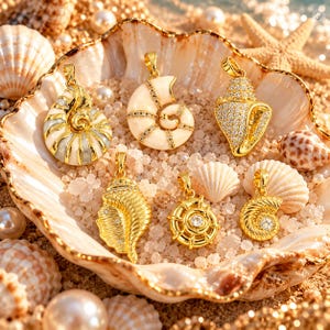 Puede incluir: Seis colgantes de metal dorado con formas de diversas conchas marinas y un timón de barco, con esmalte blanco, piedras de circonita cúbica transparentes y superficies texturizadas. Cada colgante incluye una pequeña anilla dorada superior.