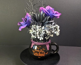 Perfectly Wicked Halloween Floral Arrangement in Cauldron Mug with Purple and Black Faux Flowers