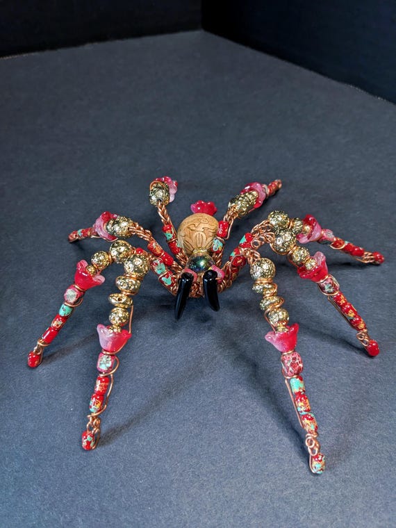 A one-of-a-kind life-sized copper spider sculpture hand-beaded in vivid red — the kind of object that stops guests dead in their tracks.