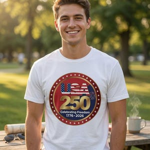 Peut inclure: Un t-shirt blanc à manches courtes arborant un motif circulaire avec le drapeau des USA en rouge, blanc et bleu, le nombre 250 en doré et le texte Celebrating Freedom 1776-2026, entouré d'une bordure d'étoiles blanches sur fond rouge.