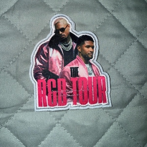 Könnte beinhalten: Ein Stoffaufnäher mit einem Fotodruck von zwei Personen in rosa Jacken und silbernen Ketten. Der Text THE R&B TOUR ist in großen, fetten, leuchtend rosa Buchstaben unten aufgedruckt, wobei darüber ein kleinerer Text zu sehen ist.