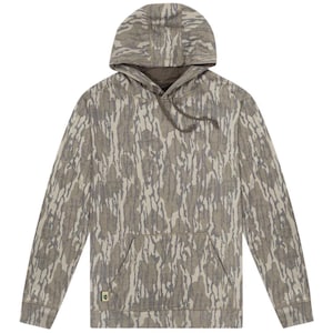 May include: A long-sleeve hooded sweatshirt featuring a tan and dark grey bark-like camouflage pattern. The pullover includes a front kangaroo pocket, a drawstring hood, and a small rectangular logo tag attached to the bottom left pocket seam.