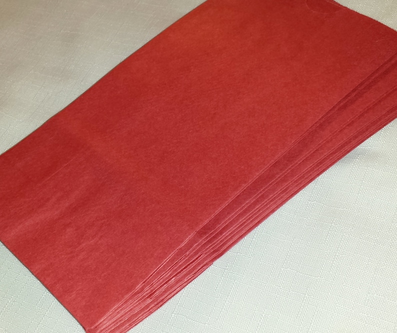 Puede incluir: Una pila de hojas de papel de seda rojas. Las hojas son rectangulares y tienen una superficie ligeramente texturizada. El papel es de un color rojo s&oacute;lido y vibrante. La pila est&aacute; cuidadosamente dispuesta, con los bordes alineados.