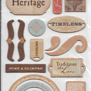 May include: Chipboard embellishments with a vintage theme. The package includes various shapes and sizes, such as oval, rectangular, and circular designs. The color palette consists of beige, brown, and light blue, with text like "Heritage" and "Timeless".