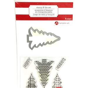 May include: A clear plastic package containing a stamp and die set for holiday crafting. The set includes a metal die-cut Christmas tree and several clear stamps with tree designs and the words "HAPPY" and "HOLIDAYS". The package has red and white stripes.