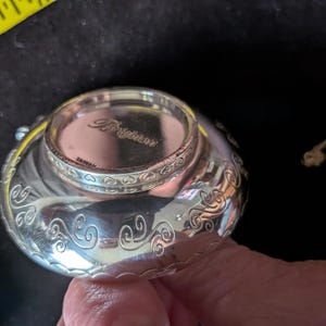 May include: A silver-toned metal bowl with a polished finish and engraved swirl patterns along the exterior. The base features the embossed text Brighton and TAIWAN. A yellow measuring tape is visible in the corner showing a 15.24 cm mark.