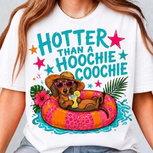 Può includere: Una t-shirt bianca con la grafica di un bassotto marrone che indossa un cappello di paglia e occhiali da sole rosa, sdraiato su un salvagente rosa e arancione maculato mentre tiene una bevanda. Il testo recita HOTTER THAN A HOOCHIE COOCHIE.