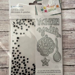 May include: A clear plastic package containing die-cutting templates for crafting. The package includes a dotted embossing folder and several metal dies, including the word "BIRTHDAY" and a cupcake. The package also includes the text "cut & emboss".