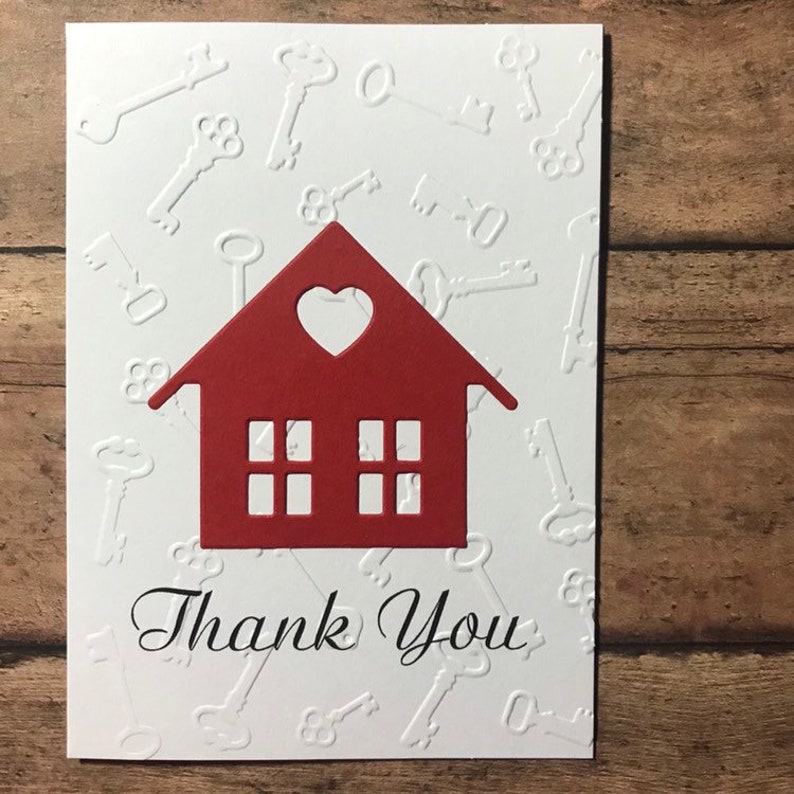 May include: A white card with a red house cutout and the words "Thank You" in black script. The background is embossed with a pattern of keys.
