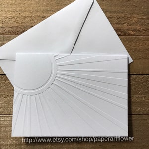 May include: A white embossed greeting card with a sunburst design, accompanied by a matching envelope. The card features a raised sun design with radiating lines. The Etsy shop URL is visible at the bottom.