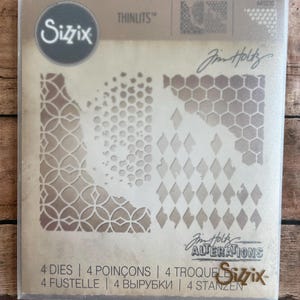 May include: A package of Sizzix Thinlits dies featuring intricate geometric patterns. The dies include designs with circles, diamonds, and honeycomb shapes. The package includes the text "Jim Holtz ALTERATIONS" and "4 DIES".
