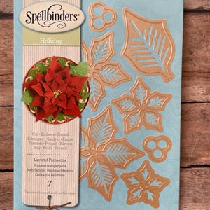 May include: A Spellbinders Holiday Layered Poinsettia metal die set package featuring seven copper-colored cutting dies in leaf and flower shapes. The packaging displays a finished red poinsettia craft project and the text S5-055.