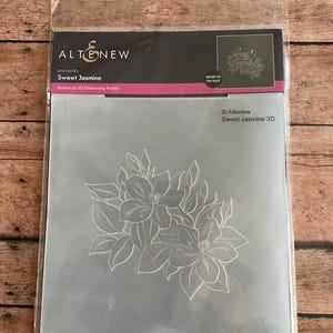 May include: A clear plastic package containing a 6x6 inch Sweet Jasmine botanical 3D embossing folder. The folder features a detailed floral design of jasmine flowers and leaves. The Altenew logo is visible at the top.
