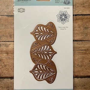 May include: A set of two gold metal die-cut stencils for creating a starburst petal doily. The package includes instructions on how to use the dies. Spellbinders $4-1055.