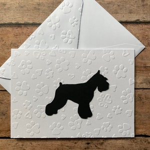 May include: A white card with a black silhouette of a miniature schnauzer dog. The card has a textured background with white paw prints and hearts.