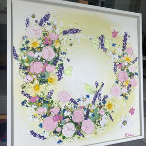 May include: A square canvas painting in a white frame featuring a circular floral arrangement on a pale yellow background. The artwork displays pink roses, purple lavender, yellow daffodils, and white flowers with green foliage, butterflies, and small bees.