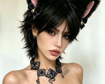 May include: A black cat ear headband featuring pink inner ears, small black bows, and gold-toned bells. The accessory is paired with a black statement necklace composed of textured square links and dangling snake-shaped charms.