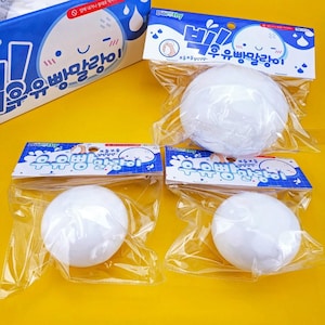 May include: Three white, spherical, soft-touch squeeze toys packaged in individual clear plastic bags with blue and white header cards featuring the text Dorothy and Korean characters. Each bag displays a cartoon character illustration.
