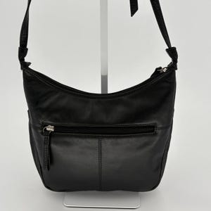 May include: A black leather hobo-style shoulder bag featuring a curved top zipper closure, a single adjustable shoulder strap with knotted ends, and a horizontal zippered exterior pocket on the front with a silver-toned metal zipper pull.