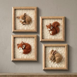 May include: Four square wooden frames containing needle-felted animal figures on a textured white background. The figures include a sleeping fawn with white spots, a curled-up squirrel, a resting fox with a white tail tip, and a sleeping rabbit.