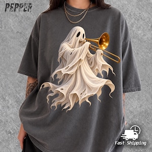 Op de afbeelding: Een antracietgrijs T-shirt met korte mouwen en een afbeelding van een witte geest die op een gouden trombone speelt. Het woord PEPPER staat in de linkerbovenhoek gedrukt. Het shirt heeft een ronde hals en een relaxte pasvorm.