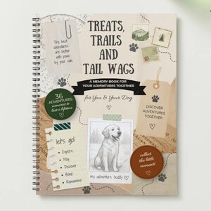 May include: A spiral-bound memory book with the title "Treats, Trails, and Tail Wags". The cover has illustrations and text, including "A Memory Book for Your Adventures Together". Features a dog illustration and the phrase "my adventure buddy".