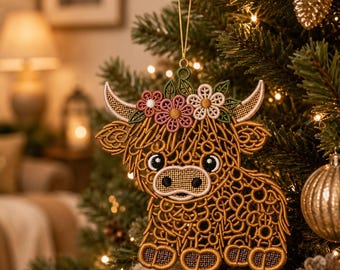 May include: A brown Highland cow ornament featuring intricate embroidery with a lace-like texture. The cow has a floral crown with pink and white flowers between its horns and is suspended by a thin gold string for hanging on a tree.
