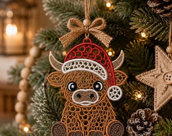 May include: A brown Highland cow ornament featuring a red and white Santa hat with a pom-pom. The cow has a detailed, lace-like embroidered texture, large black eyes, and small horns. It hangs from a jute twine string with a small burlap bow.