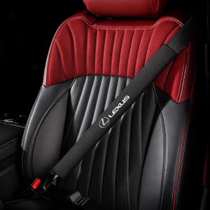 Peut inclure: Une housse de ceinture de sécurité noire arborant le logo et le texte Lexus en blanc. La housse est placée sur une sangle de ceinture diagonale, reposant contre un siège auto en cuir rouge et noir doté de surpiqûres verticales.