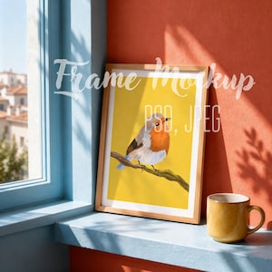 Peut inclure: Une impression encadrée représentant un rouge-gorge perché sur une branche sur un fond jaune uni. L'œuvre est présentée dans un cadre en bois clair. Le texte "Frame Mockup PSD, JPEG" est superposé sur l'image dans une police cursive blanche.