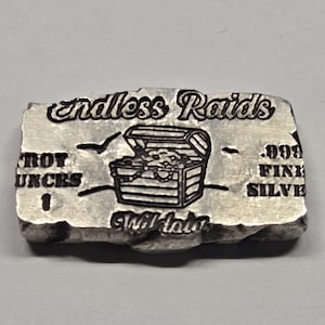 May include: A rectangular silver bar with a textured, uneven edge. The front features the text "endless Raids" at the top, a central graphic of an open treasure chest, and the text "1 TROY OUNCES" and ".999 FINE SILVER" on the sides.
