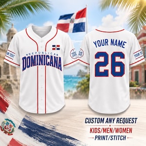 May include: A white baseball jersey with red piping, featuring the text REPUBLICA DOMINICANA in blue on the front, a small Dominican flag, and the number 26 with the text YOUR NAME on the back. The sleeves include placeholders for custom text and logos.