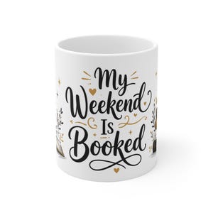 Può includere: Una tazza in ceramica bianca con testo in corsivo nero che recita My Weekend Is Booked. Il design include accenti color oro come piccoli cuori, stelle ed elementi floreali decorativi sui lati del testo, creando un aspetto pulito ed essenziale.