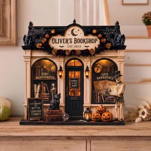 Peut inclure: Une miniature de librairie Oliver's Bookshop avec une façade noire et crème, un intérieur éclairé et un décor sur le thème d'Halloween. L'enseigne indique Oliver's Bookshop Est. 18XX. Un squelette, un chat noir, des citrouilles et des livres sont visibles.