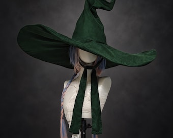 Può includere: Un cappello a punta verde scuro con una tesa larga e flessibile e lunghi nastri di tessuto che pendono. Il cappello è esposto su una testa di manichino con capelli lunghi e lisci con riflessi azzurri e rosa raccolti in una treccia.