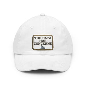 Può includere: Un cappellino da baseball bianco con una toppa rettangolare ricamata sul davanti. La toppa ha un bordo color marrone chiaro e contiene il testo scuro THE DATA HAS CONCERNS sopra un grafico a barre con una freccia verso il basso.