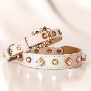May include: A pastel ombre pet collar featuring a gold-tone buckle adorned with clear rhinestones. The strap is embellished with alternating square and round gold-tone settings containing clear crystals, along with gold-tone metal rivets.