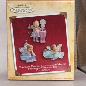 May include: A Hallmark Keepsake Ornament box featuring three fairy figurines named Karina, Laurena, and Melina from the Frostlight Faeries, Too collection. The box displays the text: Toddlers Karina, Laurena, and Melina Frostlight Faeries, Too Collection.